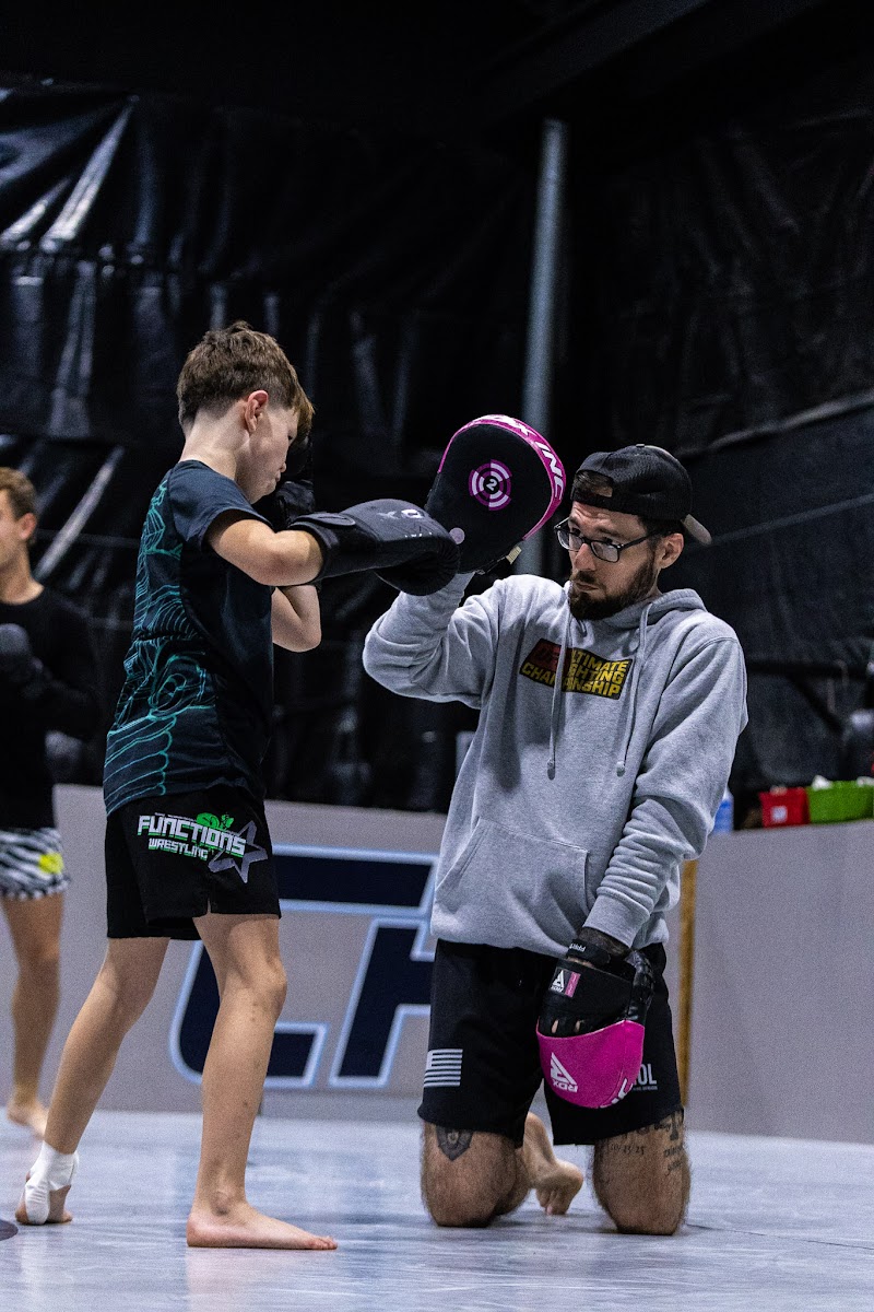 Coach holding mitts while a young student practices striking at Mad Max's Academy